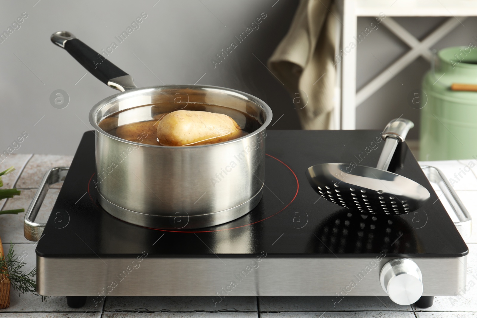 Photo of Boiling potatoes in saucepan on stove in kitchen