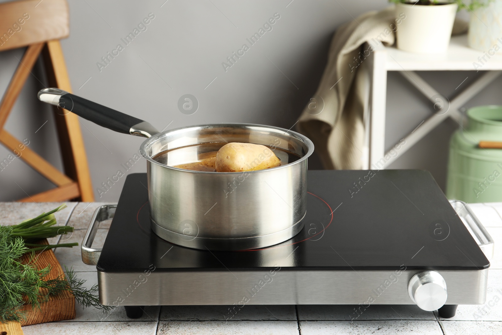 Photo of Boiling potatoes in saucepan on stove in kitchen