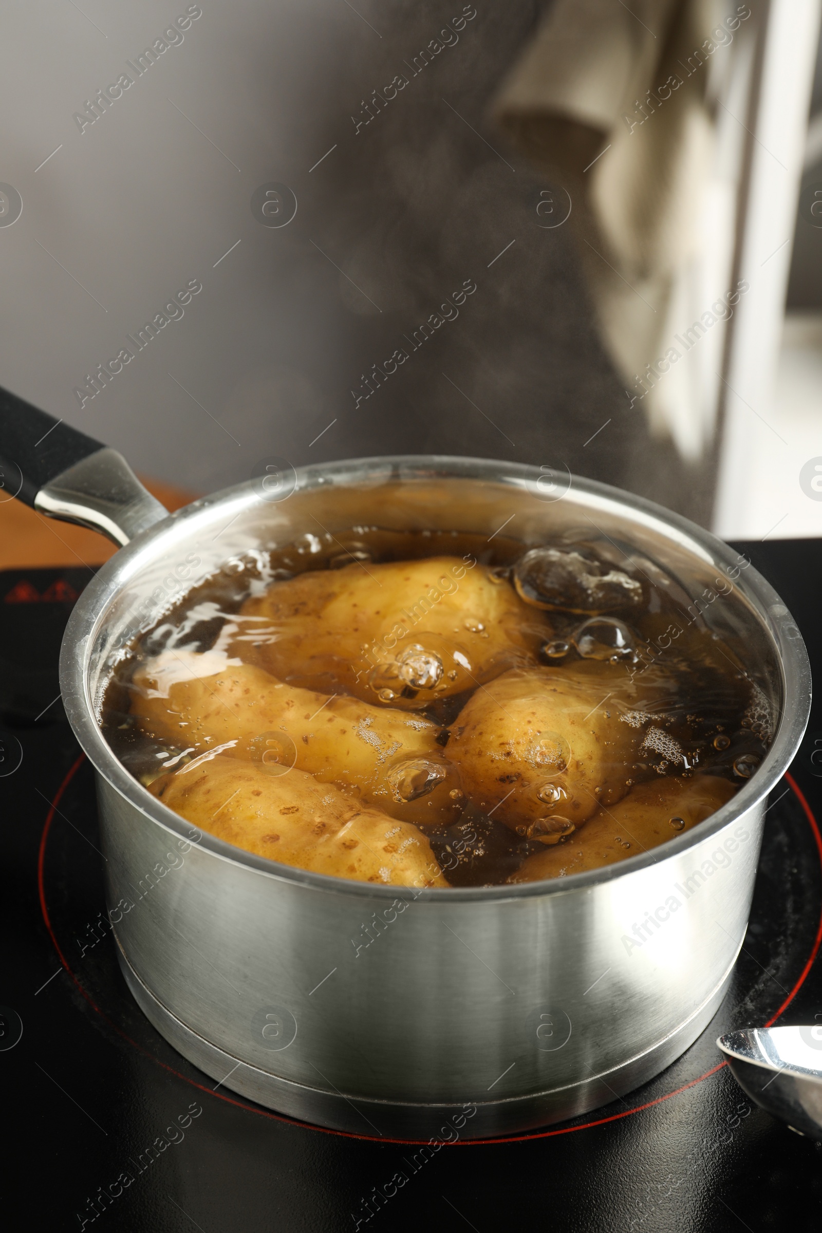 Photo of Boiling potatoes in saucepan on stove in kitchen