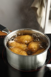 Boiling potatoes in saucepan on stove in kitchen