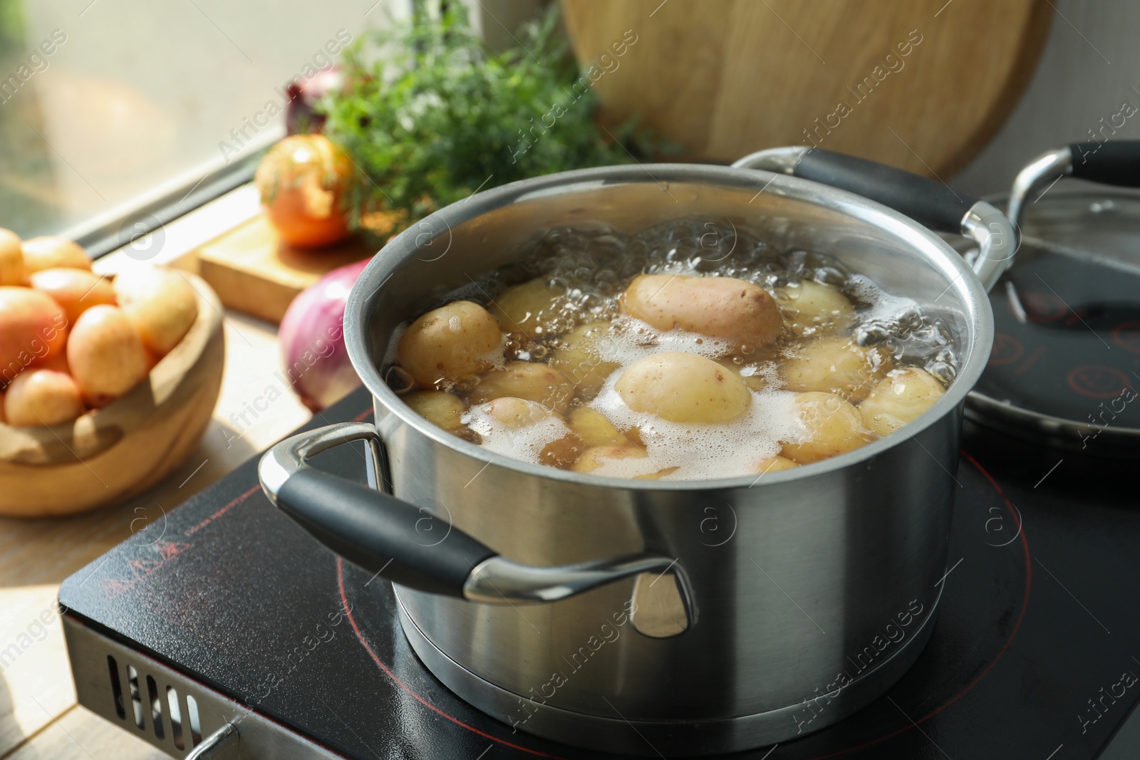 Photo of Boiling potatoes in pot on stove in kitchen