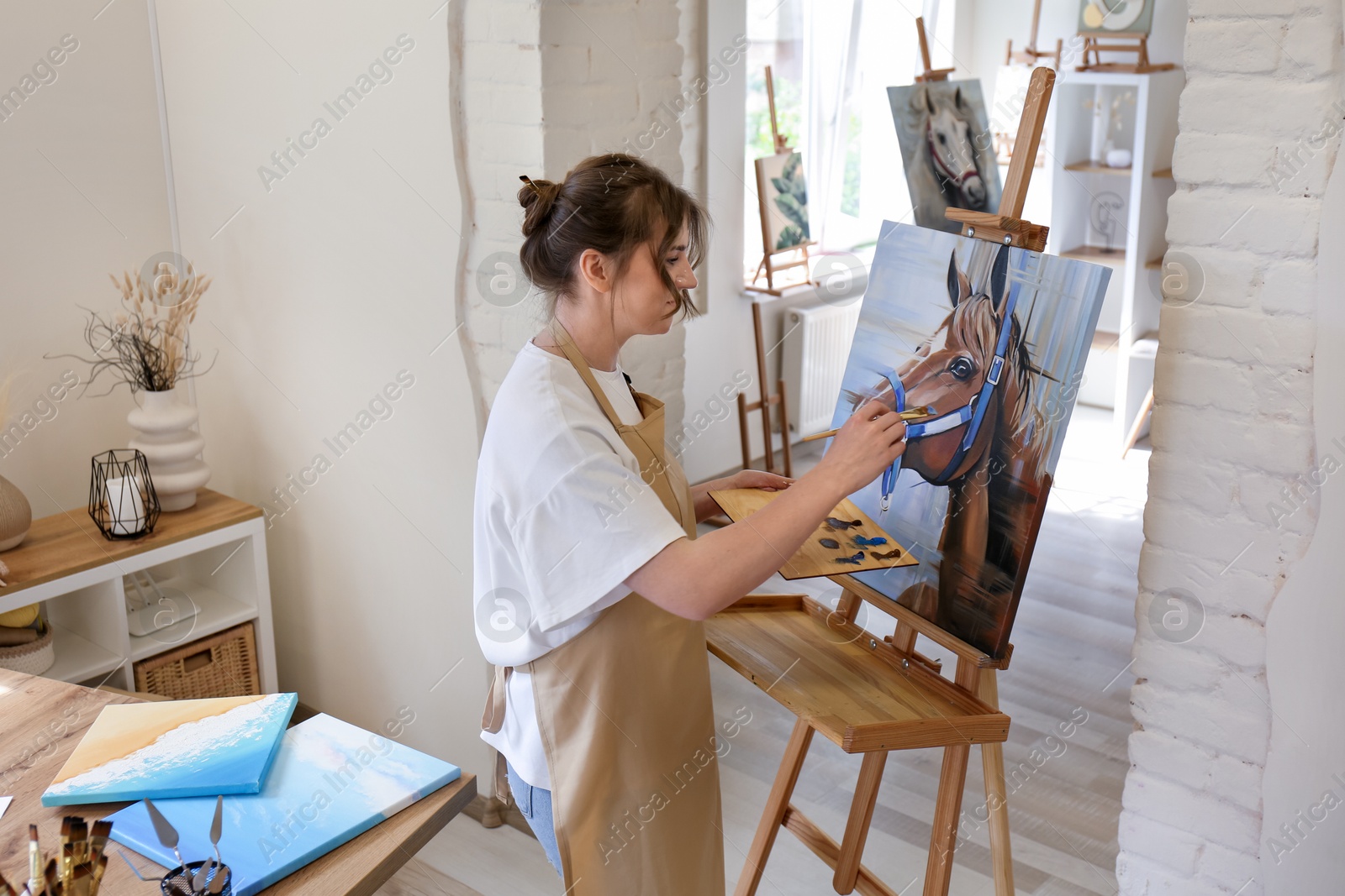 Photo of Woman drawing cute horse with brush in studio