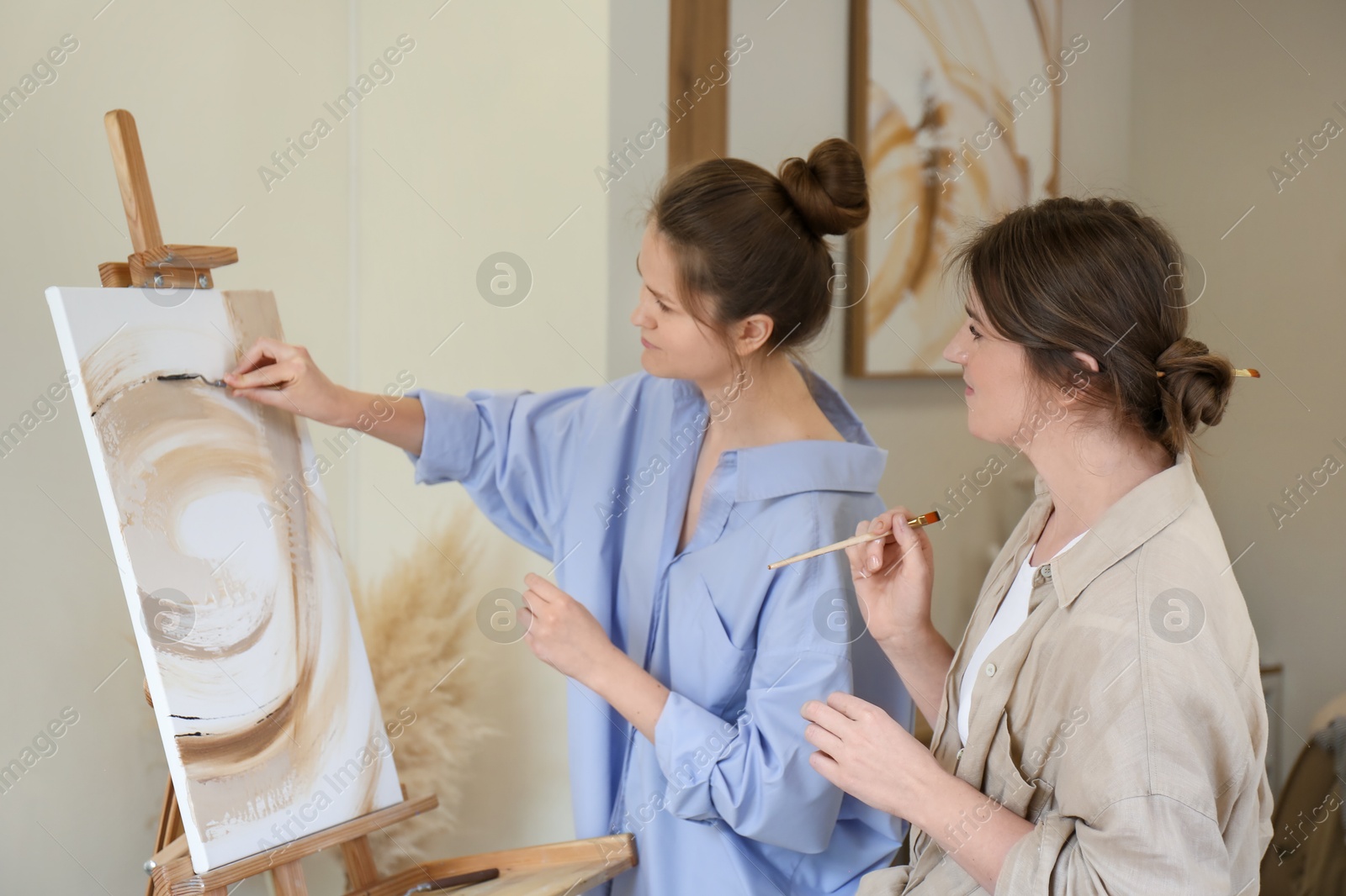 Photo of Artist teaching her student to paint in studio