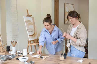 Artist teaching her student to paint in studio