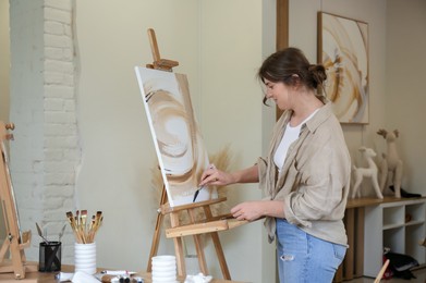 Photo of Woman with palette knife drawing picture in studio