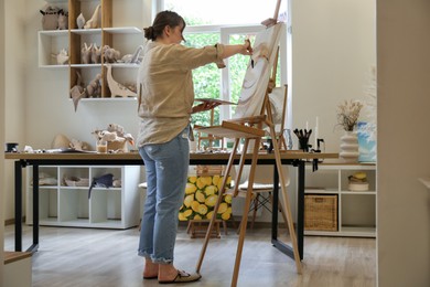 Photo of Woman drawing abstract picture on easel in studio