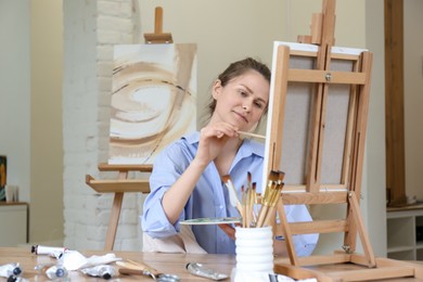 Woman with brush drawing picture at table in studio
