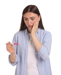 Confused woman holding pregnancy test on white background