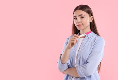 Photo of Woman holding pregnancy test on pink background, space for text