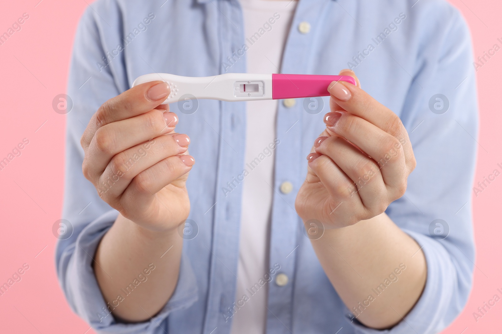 Photo of Woman holding pregnancy test on pink background, closeup