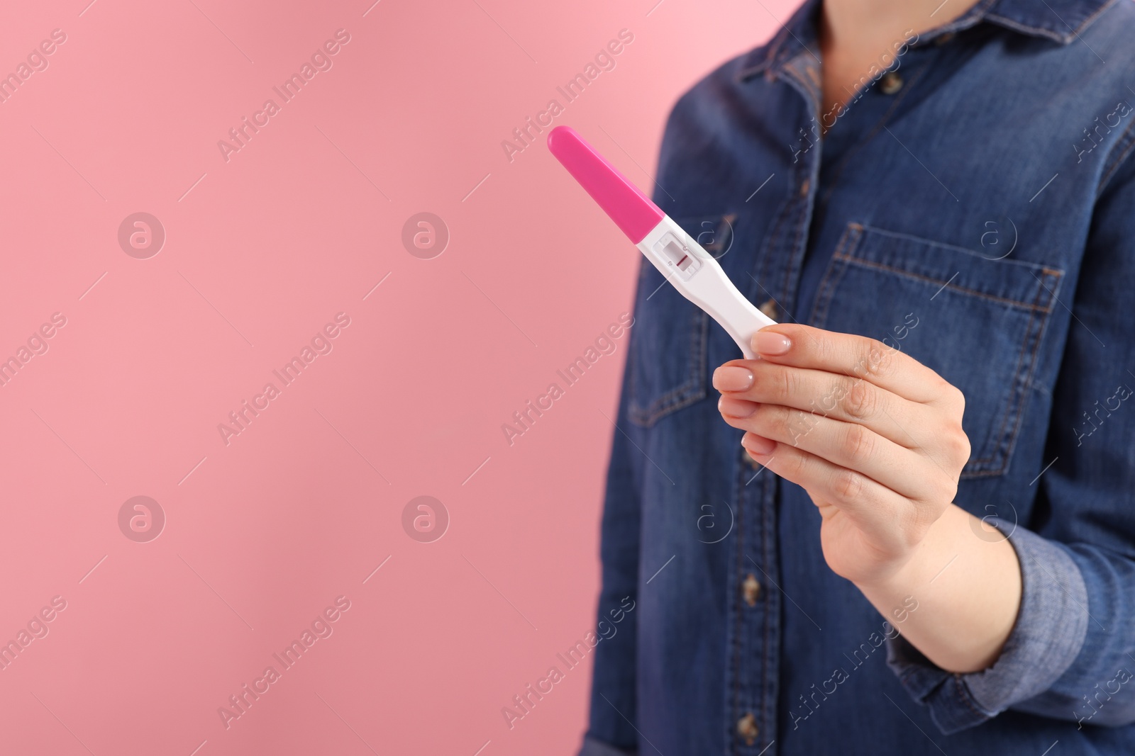 Photo of Woman holding pregnancy test on pink background, closeup. Space for text
