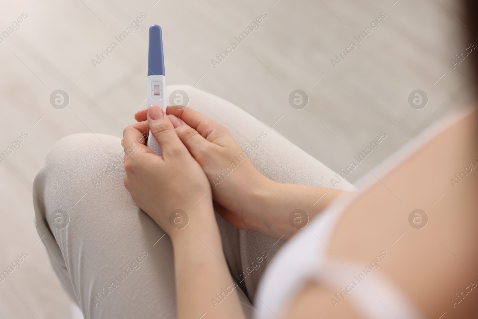 Photo of Woman holding pregnancy test in room, closeup