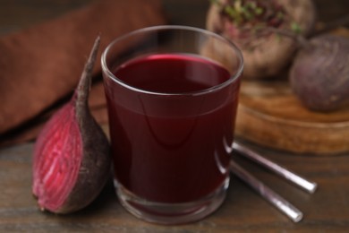 Photo of Fresh beet juice in glass, ripe vegetable and straws on wooden table, closeup