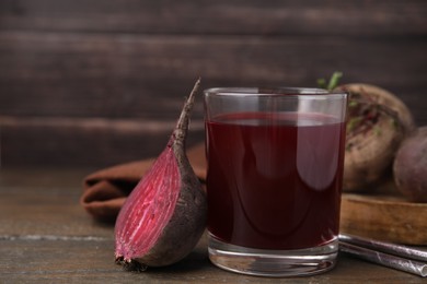 Fresh beet juice in glass, ripe vegetables and straws on wooden table, closeup