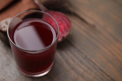 Fresh beet juice in glass on wooden table, closeup. Space for text