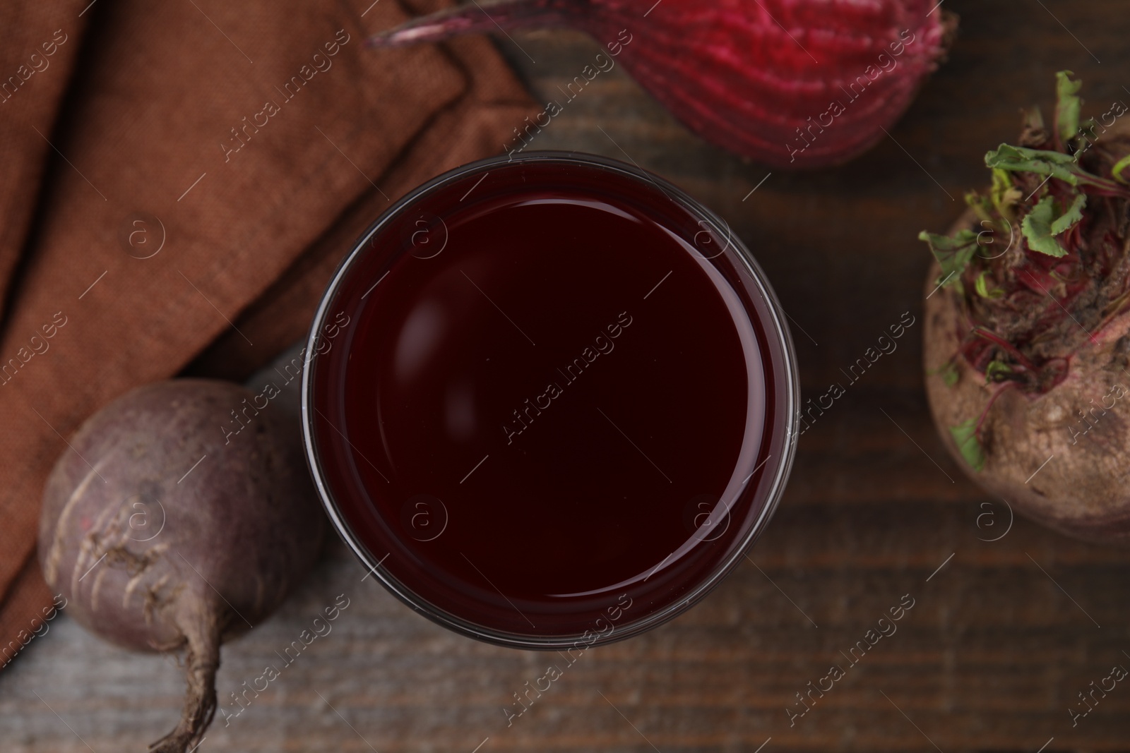 Photo of Fresh beet juice in glass and ripe vegetables on wooden table, flat lay