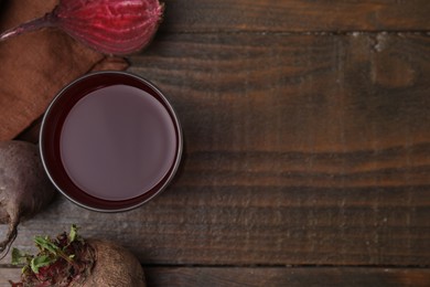 Fresh beet juice in glass and ripe vegetables on wooden table, flat lay. Space for text