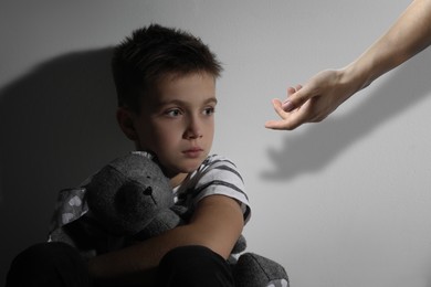 Image of Sad little child looking at outstretched man's hand indoors. Trust, support, help