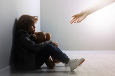 Image of Woman offering hand to sad child indoors. Trust, support, help