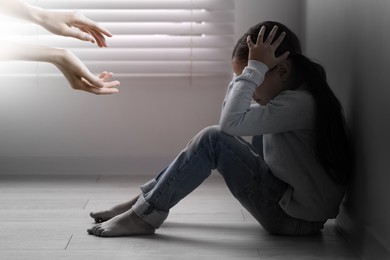 Woman lending hands to sad child indoors. Trust, support, help