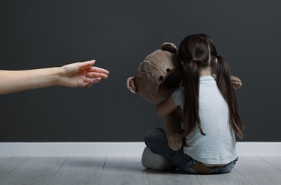 Woman offering hand to sad child indoors. Trust, support, help