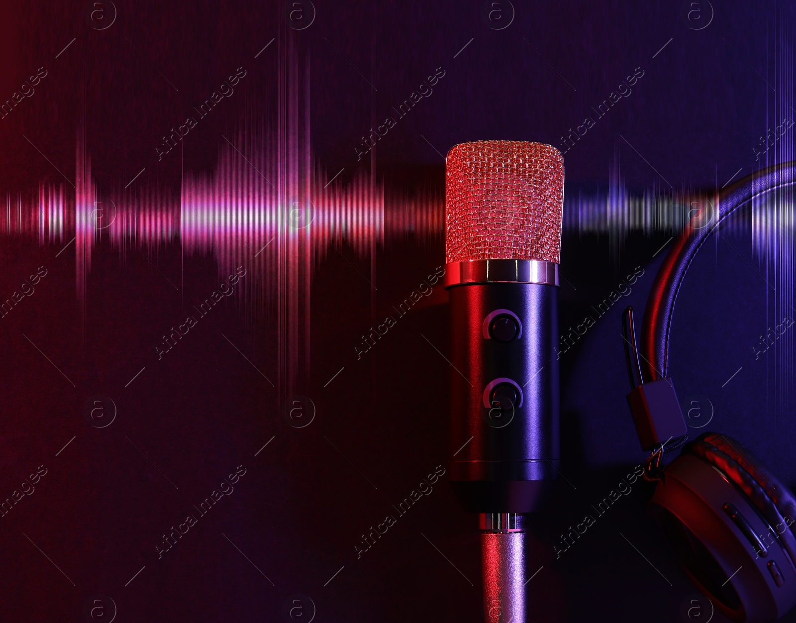 Image of Microphone, headphones and audio waveform on dark background, top view. Color toned