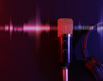 Image of Microphone, headphones and audio waveform on dark background, top view. Color toned