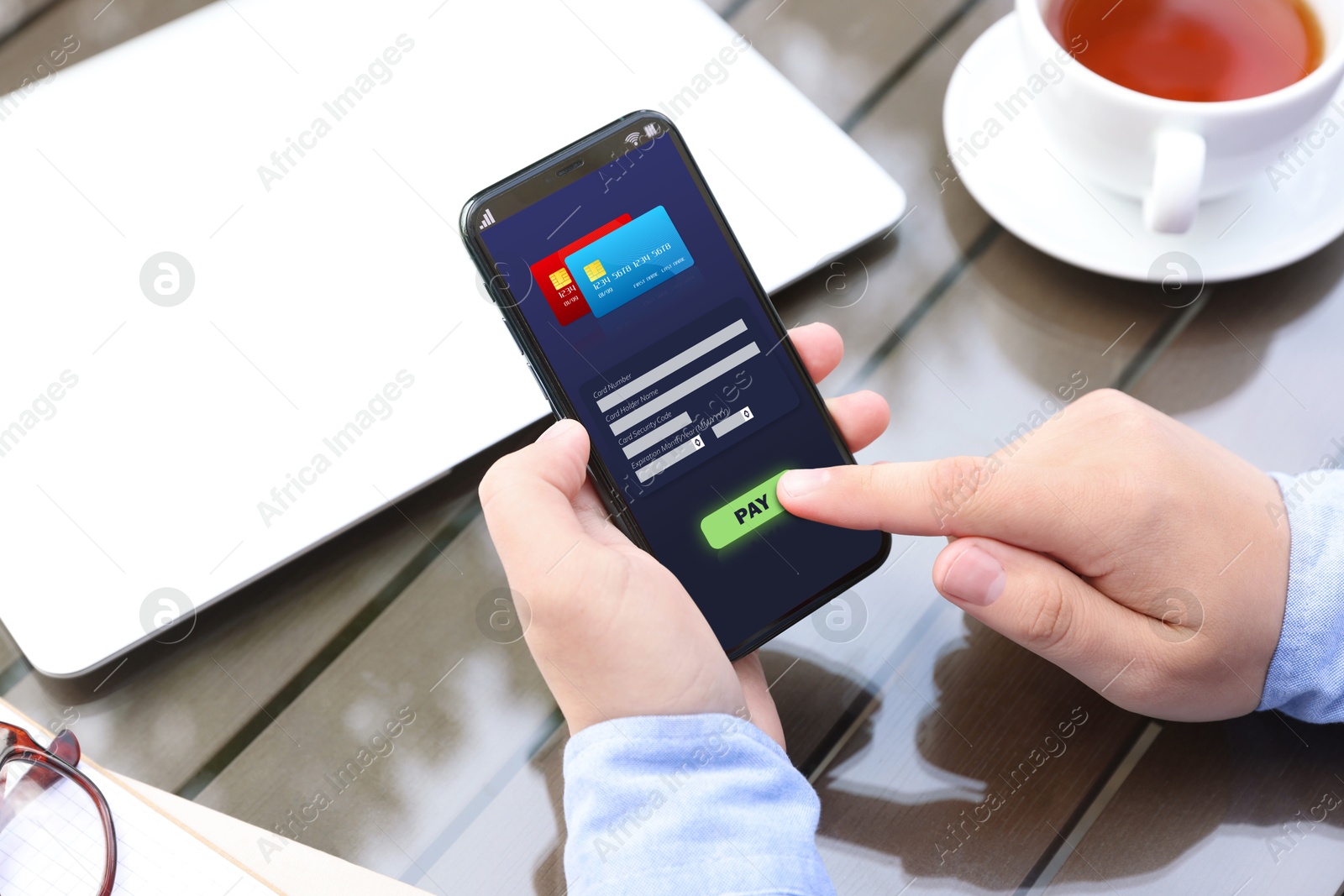 Image of Man using online payment application on mobile phone at table, closeup