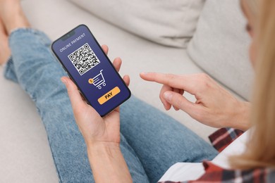 Woman using online payment application on mobile phone at home, closeup