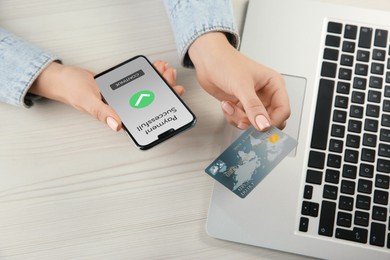 Image of Woman using online payment application on mobile phone at table, closeup