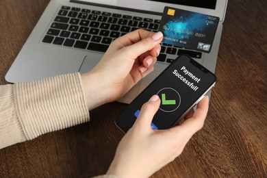 Image of Woman using online payment application on mobile phone at table, closeup