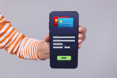 Image of Woman using online payment application on mobile phone against grey background, closeup