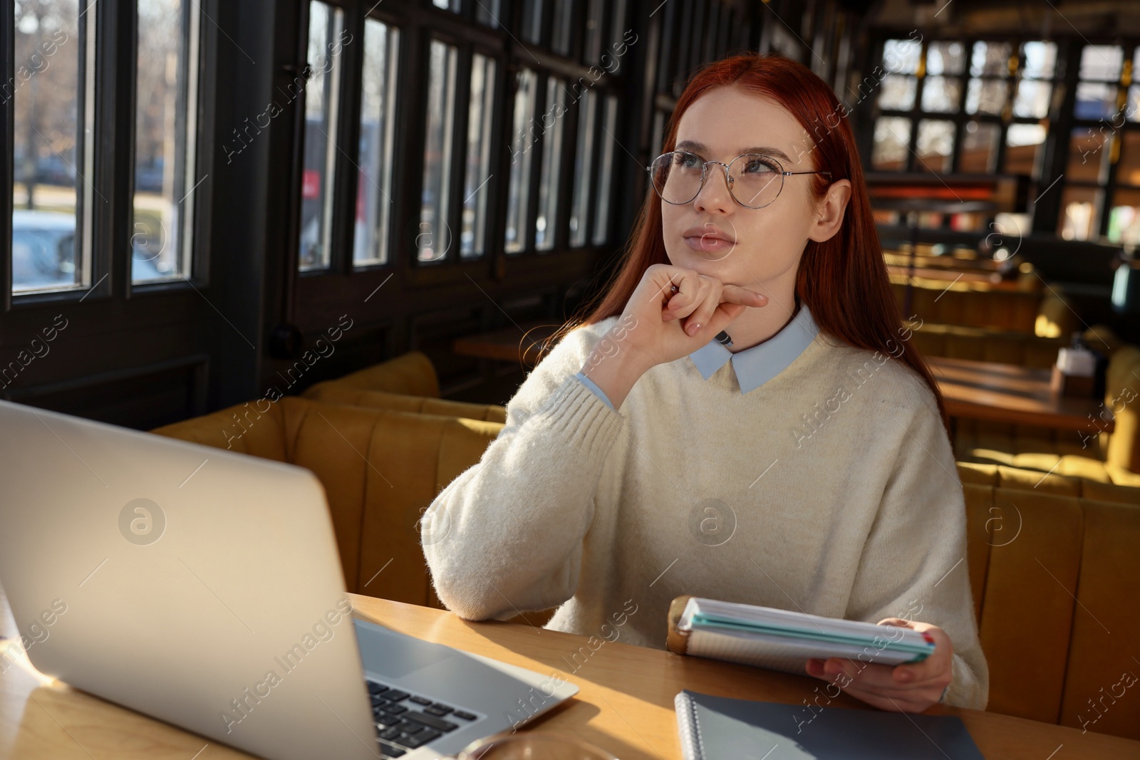 Photo of Young female student with laptop studying at table in cafe