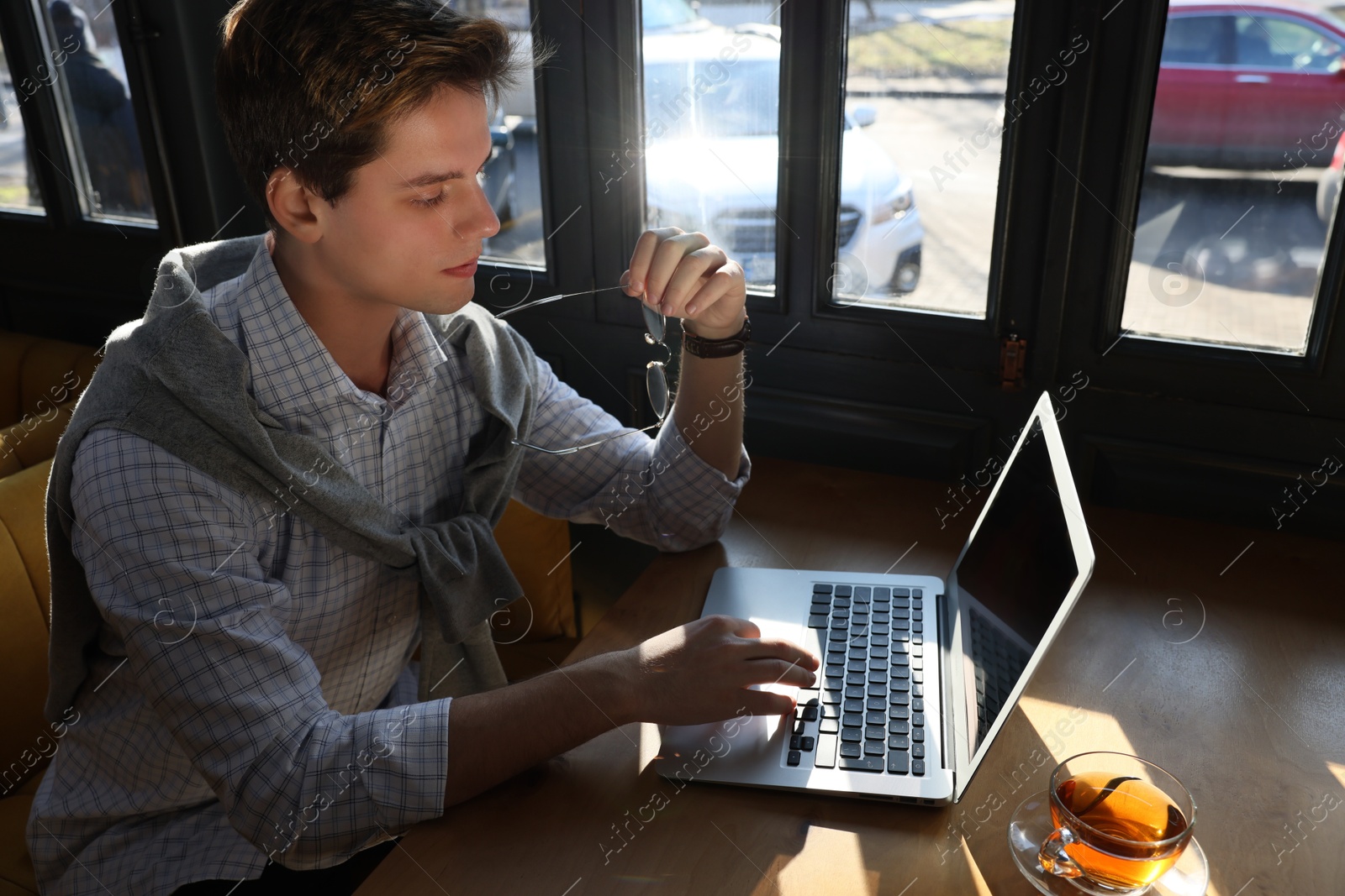 Photo of Teenage student with laptop studying at table in cafe