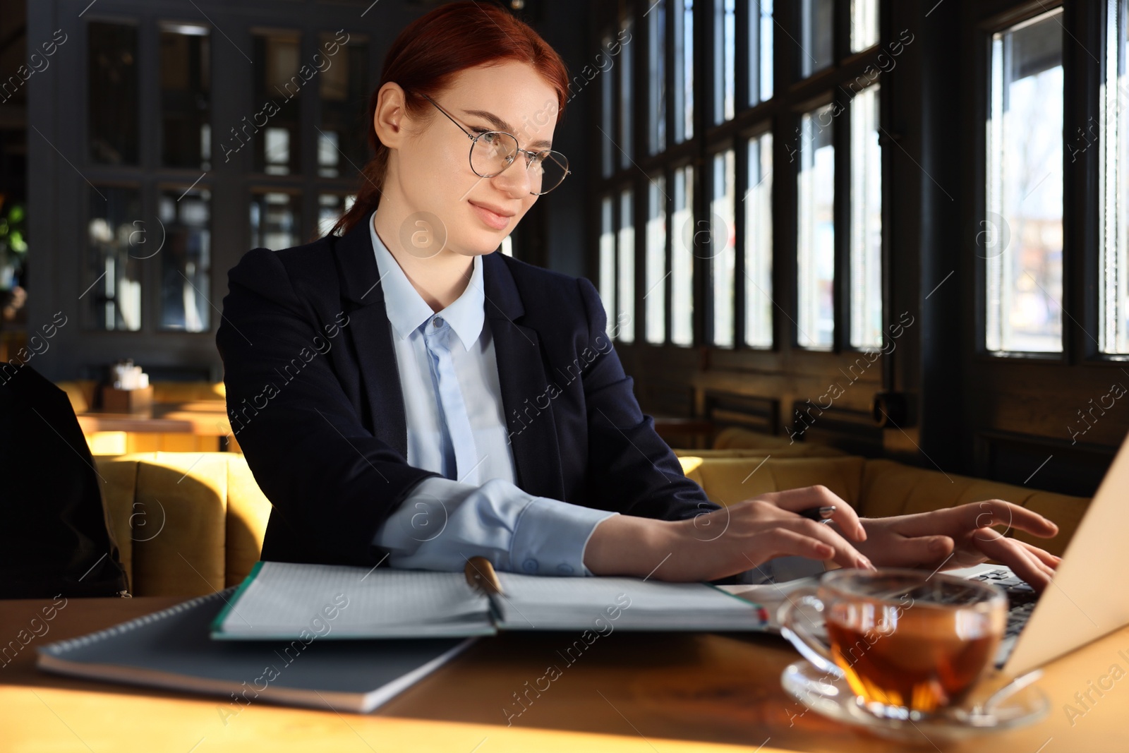 Photo of Young female student with laptop studying at table in cafe