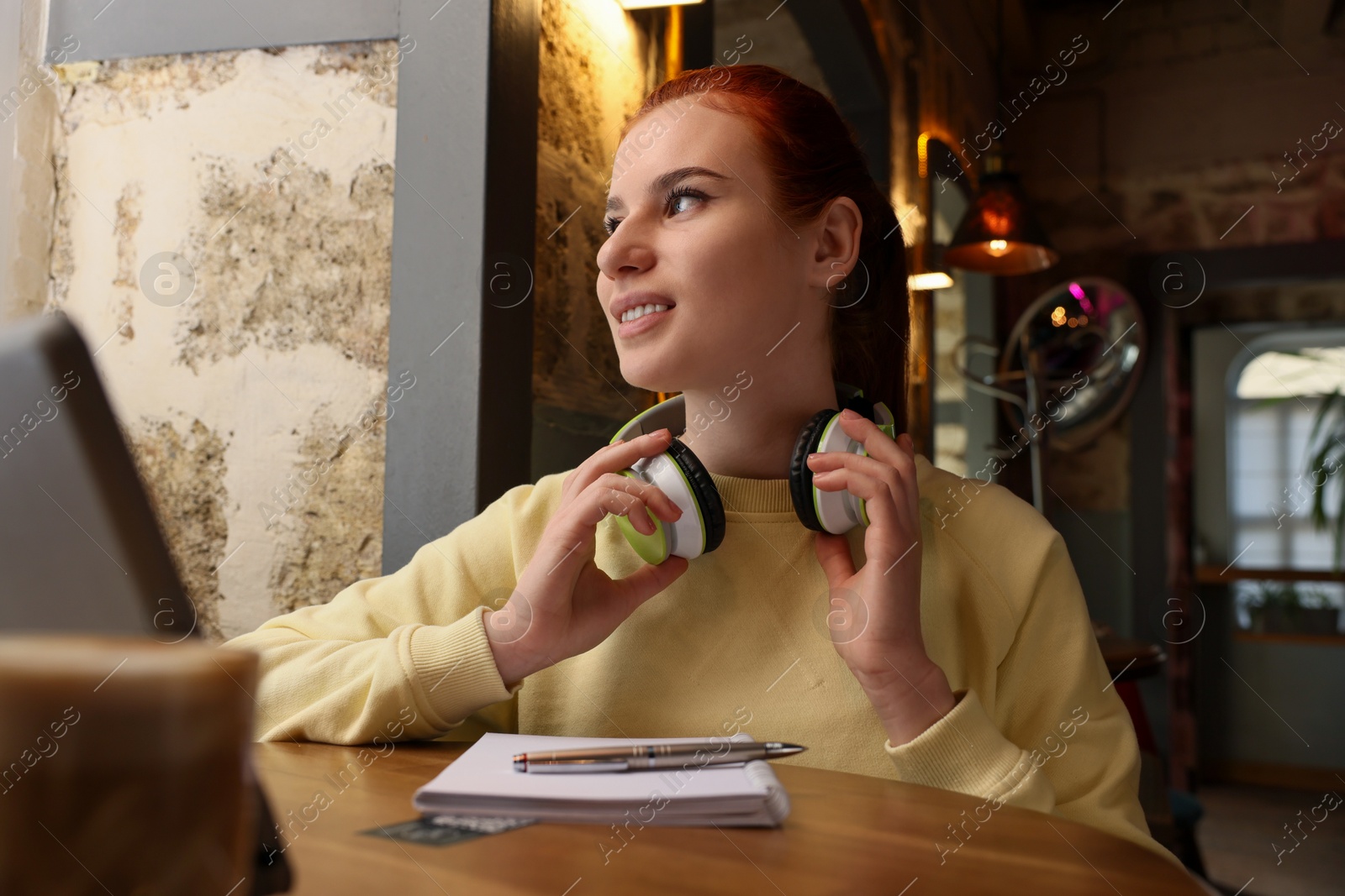 Photo of Young female student with tablet studying at table in cafe