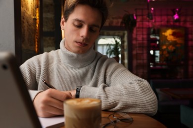 Photo of Teenage student studying at table in cafe