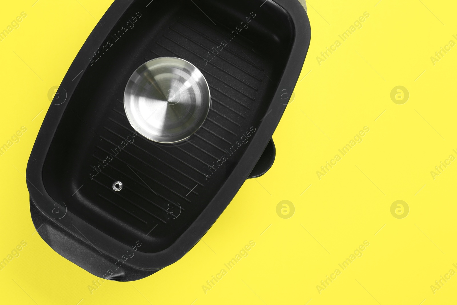 Photo of Black pot with glass lid on yellow background, top view. Space for text