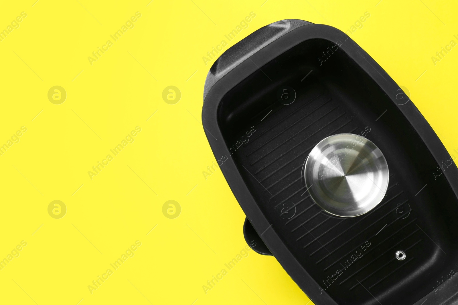 Photo of Black pot with glass lid on yellow background, top view. Space for text