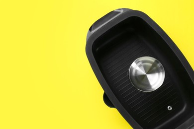 Photo of Black pot with glass lid on yellow background, top view. Space for text