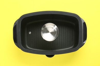 Photo of Black pot with glass lid on yellow background, top view