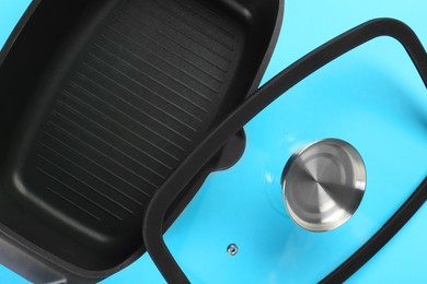 Photo of Black pot and lid on light blue background, top view