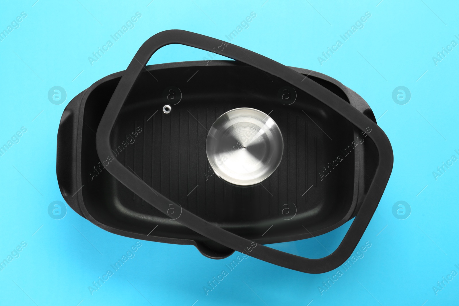 Photo of Black pot with lid on light blue background, top view