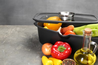 Photo of Black pot and fresh products on grey table, space for text