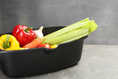 Photo of Black pot with fresh vegetables on grey table