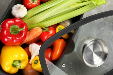 Photo of Black pot with fresh vegetables on grey table, top view