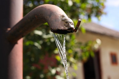 Photo of Water flowing from old tap outdoors, space for text