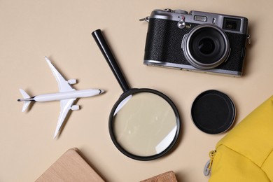 Photo of Travel blogger. Flat lay composition with vintage camera and magnifying glass on beige background