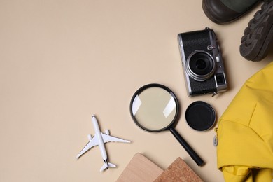 Photo of Travel blogger. Flat lay composition with vintage camera and magnifying glass on beige background, space for text