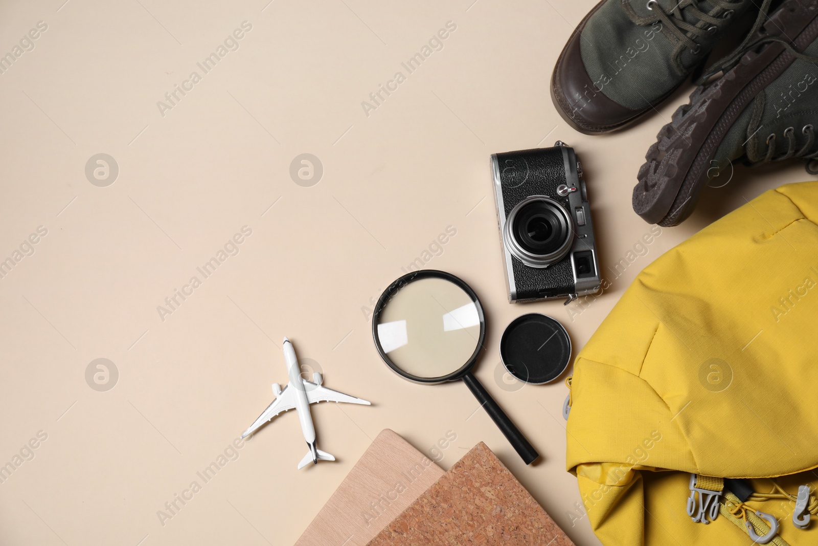 Photo of Travel blogger. Flat lay composition with vintage camera and magnifying glass on beige background, space for text